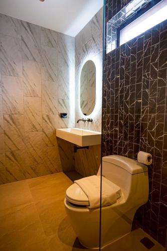 a bathroom with a toilet and a sink and a mirror at นารา พลูวิลล่า in Cha Am