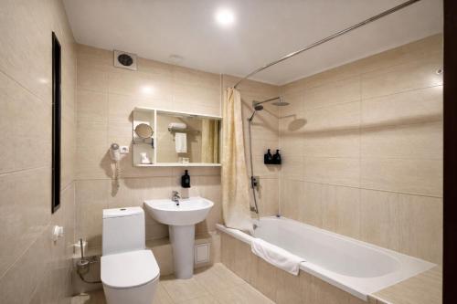 a bathroom with a sink and a toilet and a tub at Smart Hotel Bishkek in Bishkek