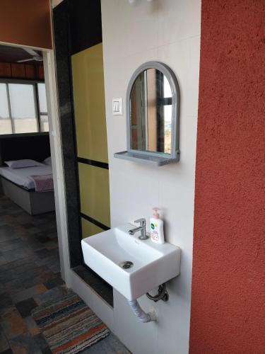 a bathroom with a white sink and a mirror at Sattva Gruha in Māngaon