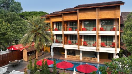 a hotel with red umbrellas and a swimming pool at March Hotel & Suite Riverside in Chiang Mai