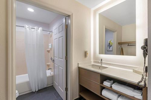 a bathroom with a sink and a mirror and a tub at Comfort Inn & Suites Savannah Airport in Savannah