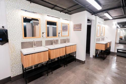 a bathroom with three sinks and two mirrors at Tequila Sunrise Podstel in Gold Coast