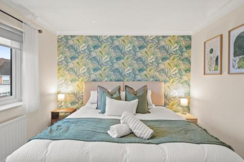 a bedroom with a large bed with a tropical wallpaper at Stylish 3Bed, in Hemel Hempstead by ARP Homes, Free Parking, Perfect for Contractors in Leverstock Green