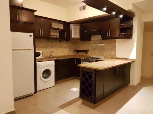 a kitchen with a white refrigerator and a dishwasher at Torino Apartments شقق تورينو in Amman