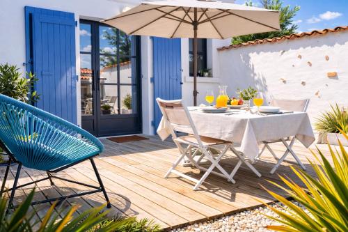 a wooden deck with a table and an umbrella at Residence Clos des Aigrettes -Appartements a 30m du Port de La Cotiniere , Ile d Oleron -commerces et plages a pied in La Cotinière
