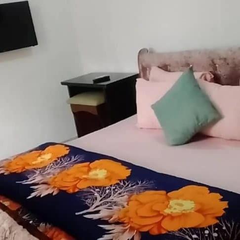 a bed with a blue blanket with orange flowers on it at Pine smart apartment Apo in Abuja