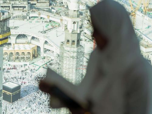 a man reads a holy book as he stands in front of the grand mosque at Zamzam Pullman Makkah in Mecca