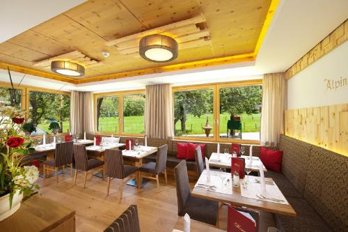 a restaurant with tables and chairs and windows at Hotel Alpina in Rauris