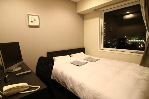 a hotel room with a bed and a phone and a window at Hotel Crown Hills Kimitsu in Kimitsu