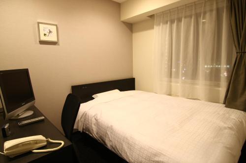 a bedroom with a bed and a phone and a television at Hotel Crown Hills Kimitsu in Kimitsu