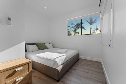 a bedroom with a bed and a picture of palm trees at The Beachside Gathering in Anna Bay