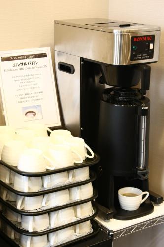 a coffee maker with a stack of plates and cups at Hotel Crown Hills Kimitsu in Kimitsu