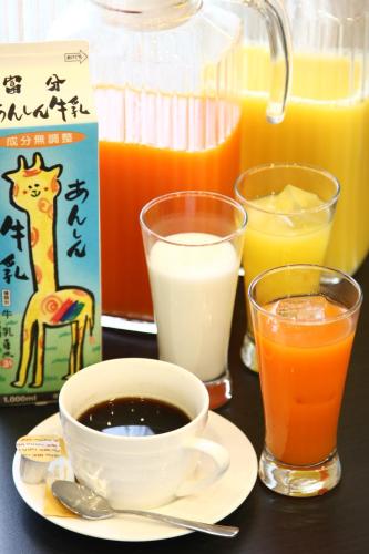 a table with a cup of coffee and two glasses of orange juice at Hotel Crown Hills Kimitsu in Kimitsu
