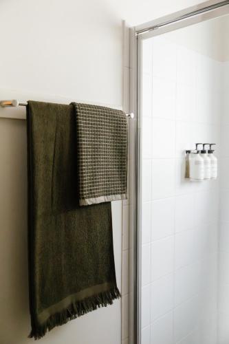 a green towel hanging on a shower curtain at The Leea, Darwin in Darwin