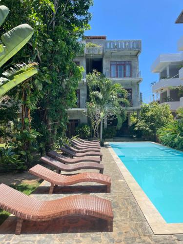 a row of lounge chairs next to a swimming pool at Surf Gangs Arugambay in Arugam Bay