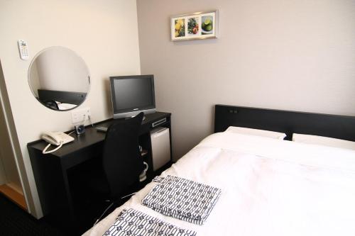 a bedroom with a bed and a desk with a mirror at Hotel Crown Hills Kimitsu in Kimitsu