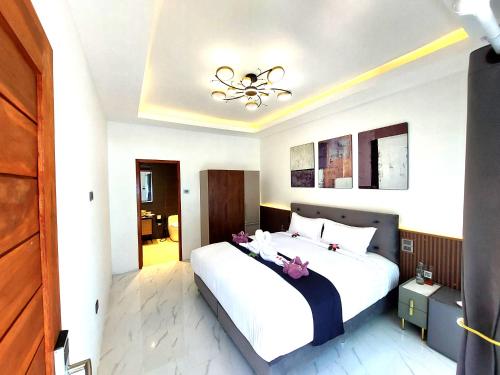 a bedroom with a large white bed and a chandelier at Samma Karuna Beach & Wellness Resort - Intoxicants free in Srithanu