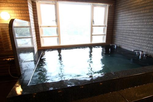 a bath tub in a room with a window at Hotel Crown Hills Kimitsu in Kimitsu