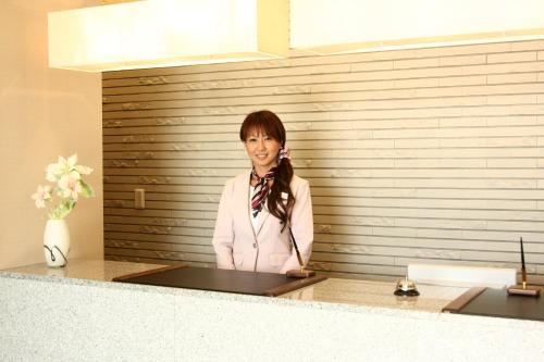 a woman standing behind a counter in a room at Hotel Crown Hills Kimitsu in Kimitsu