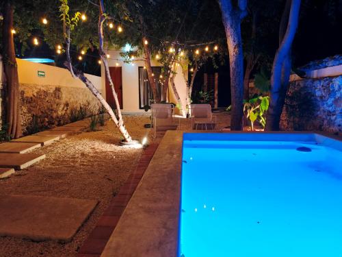 a swimming pool in a yard at night with lights at Villa Lara Palacios, tu oasis en Mérida in Mérida