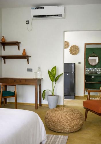a bedroom with a bed and a desk and a plant at Drop Inn Studios in Ahangama