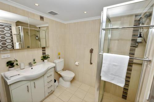 a bathroom with a toilet and a sink and a shower at Sunset Stunner Marina Views in Larrakeyah