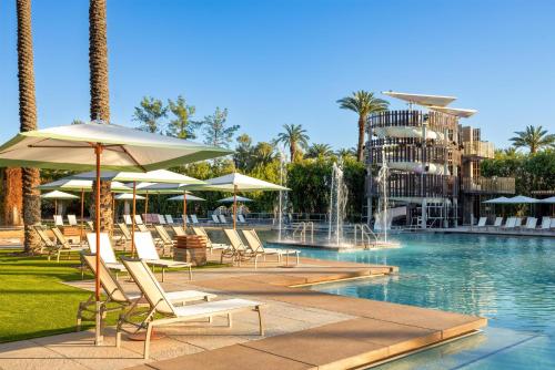 a pool with chairs and umbrellas next to a resort at Grand Hyatt Scottsdale Resort in Scottsdale