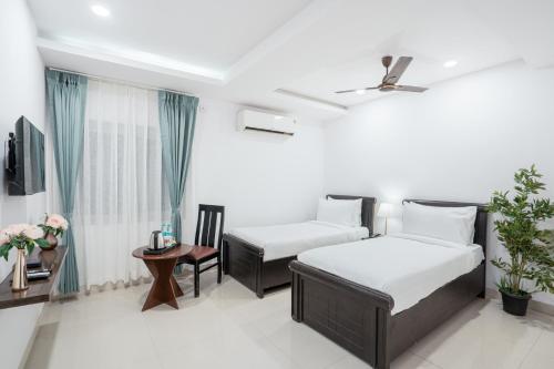a bedroom with two beds and a table and a tv at RCC Hotels Parkview Inn Miyapur in Lingampalli