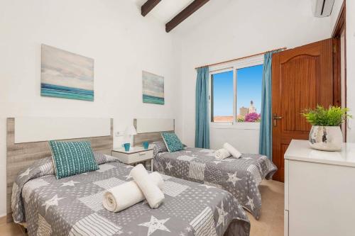 two beds in a room with a window at Villa Pearla by Villa Plus in Cala en Porter