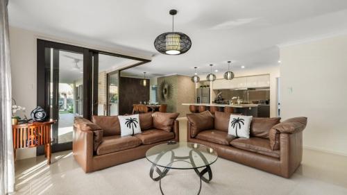 a living room with two brown couches and a glass table at The Cabana Oasis in Woorim
