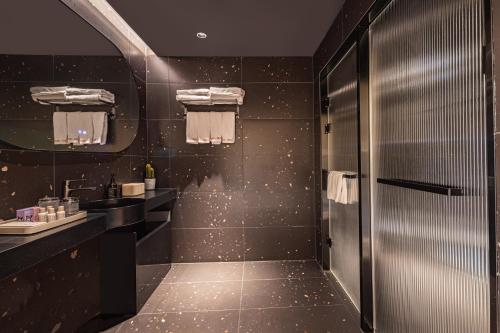 a black bathroom with a sink and a mirror at Yangshuo B&G Hotel-Exclusive location,Roof Top Viewing Terrace,Seasonal swimming pool,Free Self-Service Laundry & Drying, Entrance Ticket Serivce, Local Trip plan,E-Scooter& English Customer Service in Yangshuo