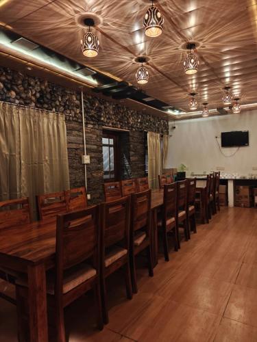 a dining room with a long wooden table and chairs at The Himalayan Majesty Hotel in Chopta