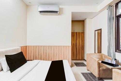 a bedroom with a bed and a chair at Collection O Rispana Pul Dehradun Formerly Hotel Square 1 in Clement Town