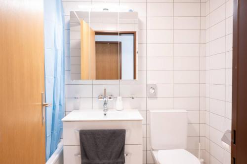 a white bathroom with a sink and a toilet at Central12 Apartment - Free Parking in Thun
