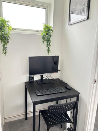 a desk with a computer monitor and a chair at Cosy one bed Flat in Stevenage in Stevenage