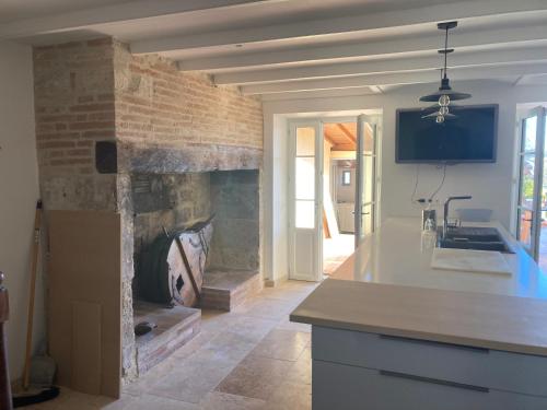 a kitchen with a stone fireplace in a room at Oasis de Compostelle in Lauzerte