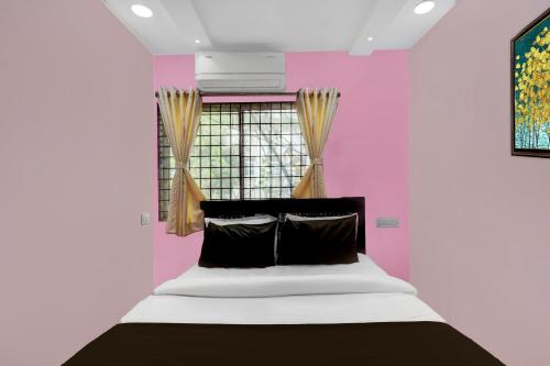 a bed in a room with a pink wall at Hotel O Lakdikapul Near Birla Mandir in Hyderabad