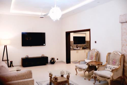 a living room with a tv and chairs and a table at The Grandeur Suite 1 in Rawalpindi