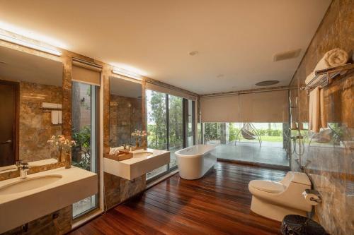 a bathroom with two sinks and a tub and a toilet at Villa Owner tại khu nghỉ dưỡng sinh thái Đại Lải Resort in Ngọc Quang