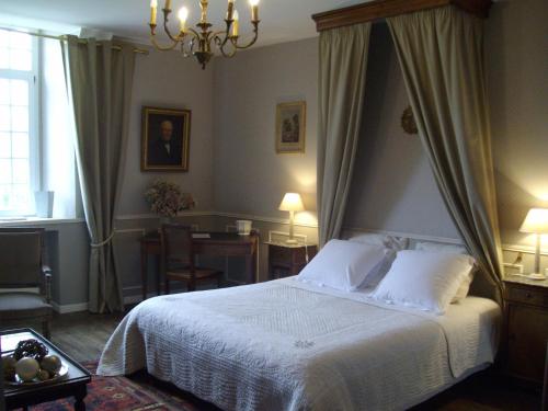 a bedroom with a white bed and a table with a table at Manoir de la Baronnie in Saint Malo