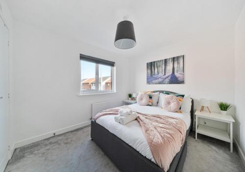 a white bedroom with a bed with pink pillows at The Nest Retreat Exeter in Exeter