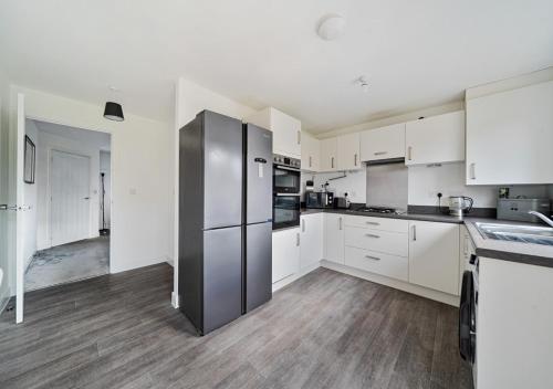 a kitchen with white cabinets and a stainless steel refrigerator at The Nest Retreat Exeter in Exeter