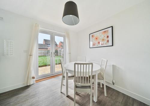 a dining room with a white table and chairs and a window at The Nest Retreat Exeter in Exeter