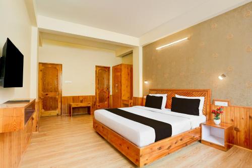 a bedroom with a large bed and a television at Hotel O Model Town Road in Manāli