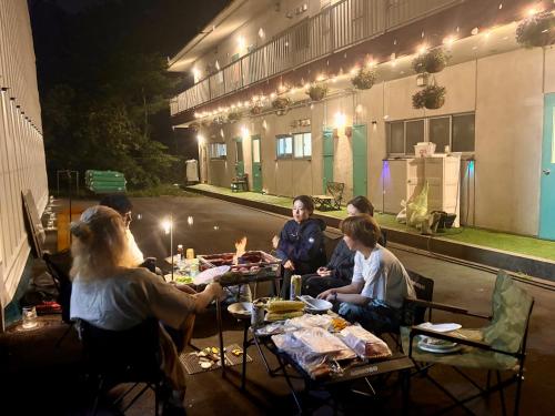 a group of people sitting at a table in front of a building at FUJI Forest House103 in Gotemba