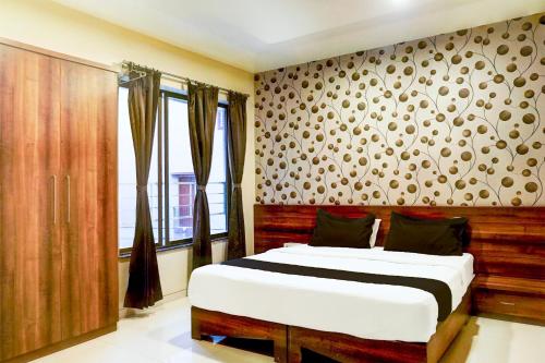 a bedroom with a bed in a room with a wall at Super Townhouse Oak Viman Nagar Formerly Kuber Inn in Pune