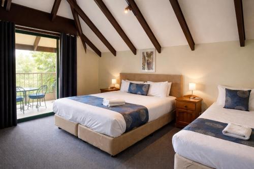 a bedroom with two beds and a balcony at Hahndorf Motel in Hahndorf