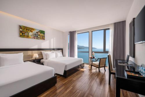 a hotel room with two beds and a desk at DAO NGOC BEACH HOTEL Da Nang in Danang