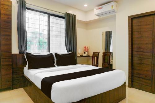 a bedroom with a large bed in front of a window at Super Hotel O Laxman Nagar Baner in Pune