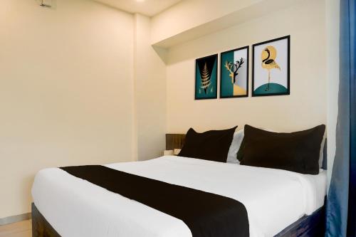 a bedroom with a white bed with black pillows at Super Hotel O Laxman Nagar Baner in Pune